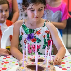 Birthday child blowing out candles on cake surrounded by friends at Flipz Academy Gold Coast